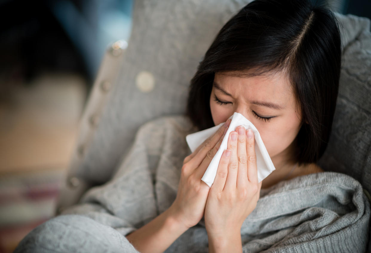 Sick woman with a cold blowing her nose.