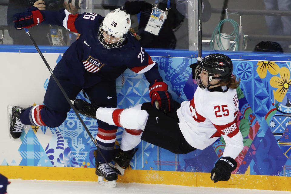 Kendall Coyne of the Untied States collides with Alina Muller of Switzerland against the boards during the first period of the 2014 Winter Olympics women's ice hockey game at Shayba Arena, Monday, Feb. 10, 2014, in Sochi, Russia. (AP Photo/Petr David Josek)