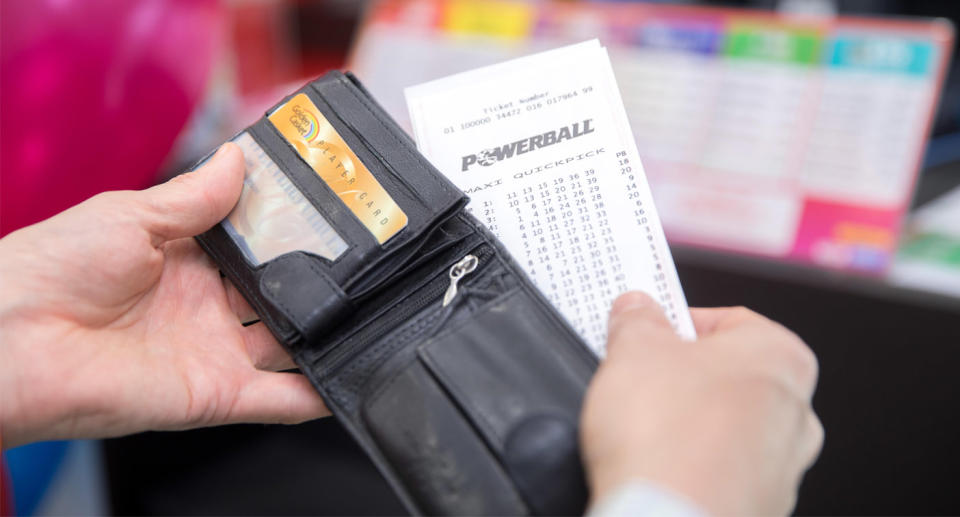 Pictured is a Powerball in a man's wallet as the search for the Victorian $36 million winner continues.