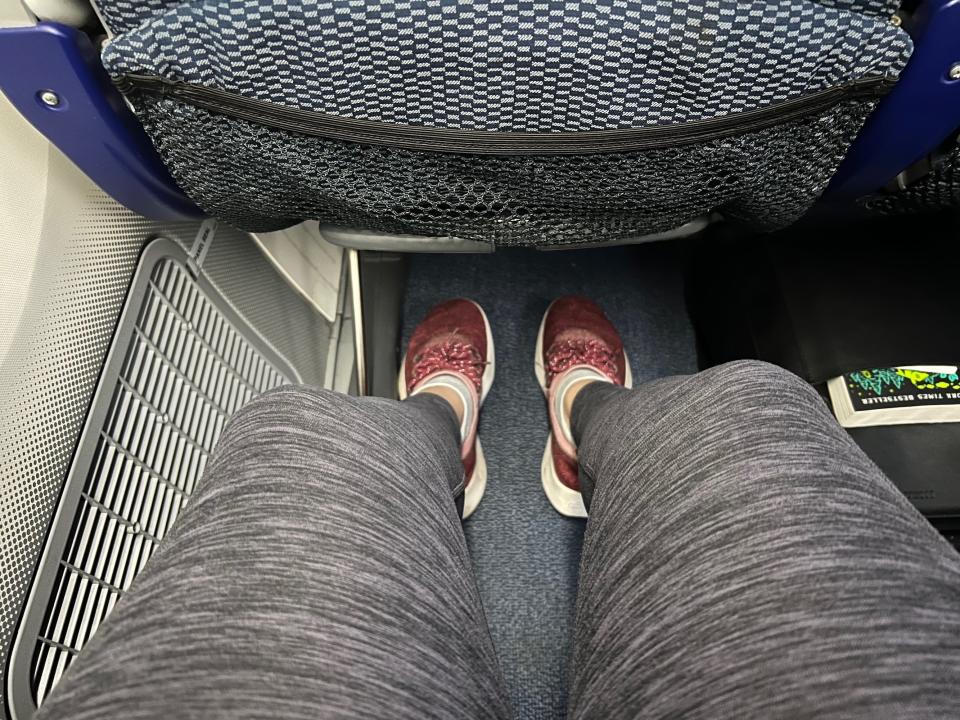 The author's legs stretch out, showing the space between her knees and the seatback.