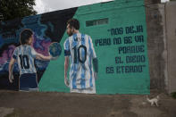 A mural depicts the late soccer star Diego Maradona, left, and Lionel Messi, with a message that reads in Spanish, "He has left us, but he is not gone because Diego is eternal," outside the "Estrella de Fiorito" club, Maradona's first club, in the Fiorito neighborhood of Buenos Aires, Argentina, Thursday, Nov. 25, 2021, on the one-year anniversary of the soccer legend's death. (AP Photo/Rodrigo Abd)