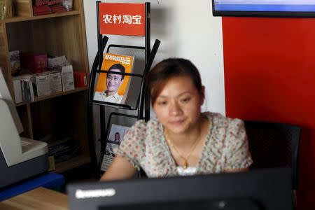 Zheng Liying looks at a computer screen in front of a picture of Alibaba founder Jack Ma, seen on the cover of a publication, at Zheng's Alibaba rural service centre in Jinjia Village, Tonglu, Zhejiang province, China, July 20, 2015. REUTERS/Aly Song