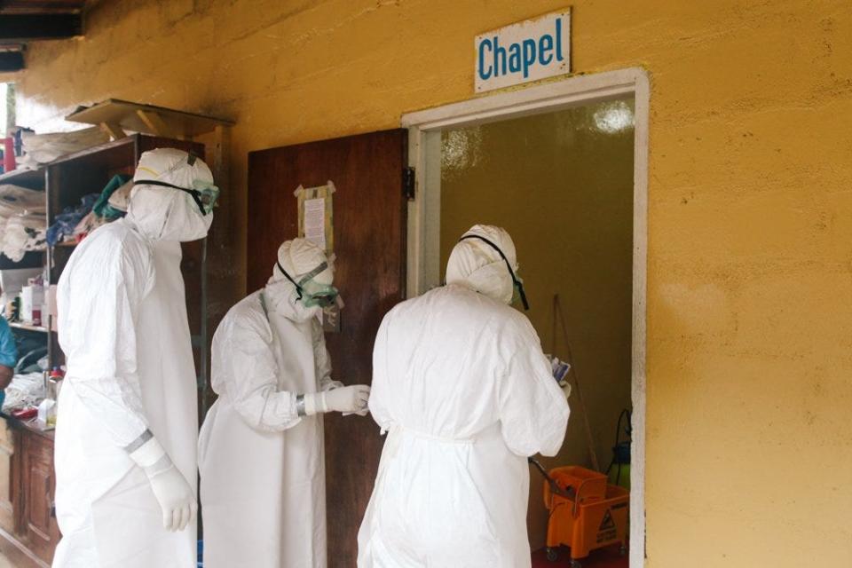 In this 2014 photo, Dr. John Fankhauser, far left, enters a chapel converted into an isolation unit for Ebola patients in Liberia.