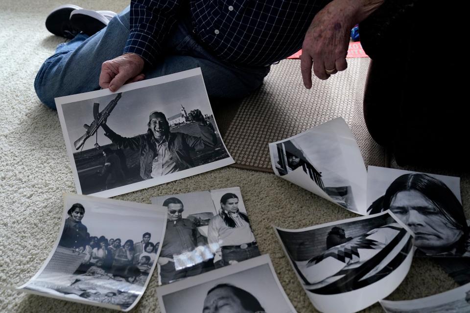 Retired Associated Press Photographer Jim Mone sits with prints of his photos taken from his coverage at Wounded Knee, Friday, Feb. 24, 2023, in Bloomington, Minn. On Feb. 27, 1973, members of the American Indian Movement took over the town of Wounded Knee, starting a 71-day occupation on the Pine Ridge Indian Reservation in South Dakota. Mone was there to capture images of the standoff as it stretched into weeks. (AP Photo/Abbie Parr)