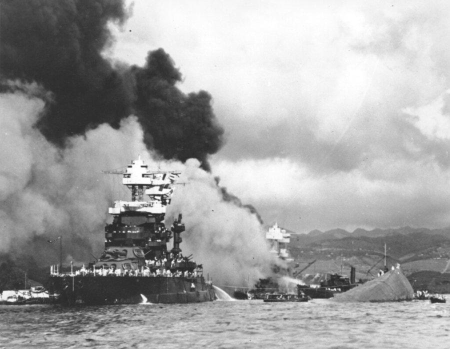 FILE – In this Dec. 7, 1941, file photo, part of the hull of the capsized USS Oklahoma is seen at right as the battleship USS West Virginia, center, begins to sink after suffering heavy damage, while the USS Maryland, left, is still afloat in Pearl Harbor, Oahu, Hawaii. Pearl Harbor survivors and World War II veterans are gathering in Hawaii this week to remember those killed in the Dec. 7, 1941 attack. Those attending will observe a moment of silence at 7:55 a.m., the minute the bombing began. The ceremony will mark the 80th anniversary of the attack that launched the U.S. into World War II. (U.S. Navy via AP, File)