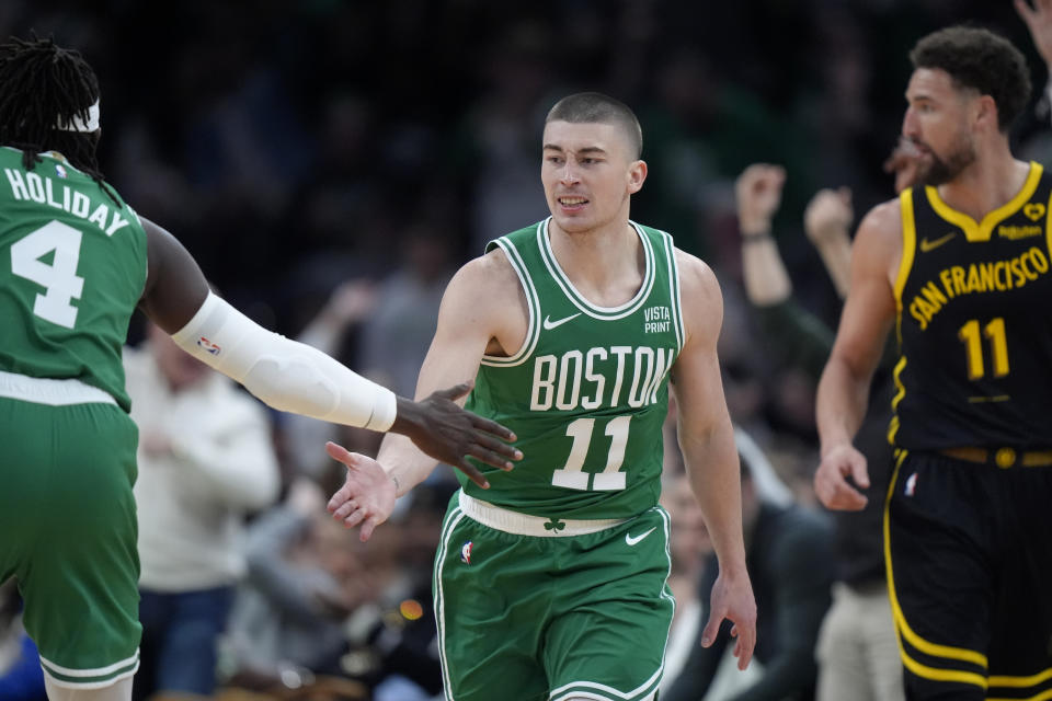 Boston Celtics guard Payton Pritchard, center, celebrates with guard Jrue Holiday, left, in front of Golden State Warriors guard Klay Thompson, right, after scoring in the first half of an NBA basketball game, Sunday, March 3, 2024, in Boston. (AP Photo/Steven Senne)