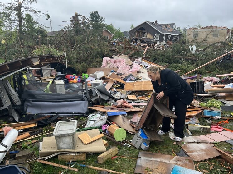 Theresa Haske sorts through debris from what was her garage after a tornado tore through Gaylord, Mich., Friday, May 20, 2022. (John Russell/Detroit News via AP)