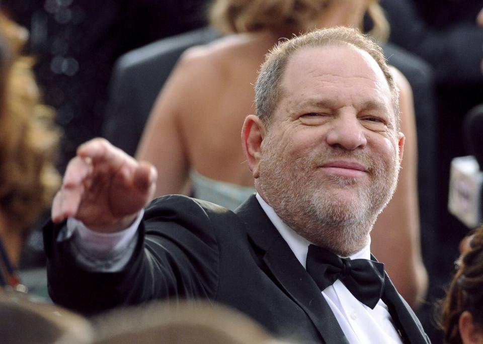 A man in a tuxedo points to someone as he arrives at the Oscars