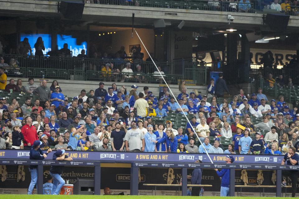 Someone on the Toronto Blue Jays bench tries to get Vladimir Guerrero Jr.'s bat down from a net during the fifth inning of a baseball game against the Milwaukee Brewers Monday, June 10, 2024, in Milwaukee. (AP Photo/Morry Gash)