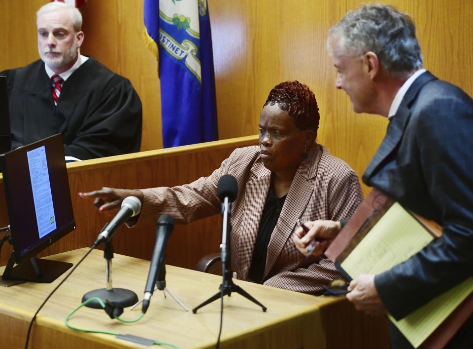 Bridgeport city employee Wanda Geter-Pataky, center, works with her lawyer, John R. Gulash, right, to know which questions to answer so as not to incriminate herself during her testimony in Bridgeport Democratic Primary Mayoral candidate John Gomes' challenge of absentee ballots in Superior Court in Bridgeport, Conn., Friday, Oct. 13, 2023. Geter-Pataky was shown video clips of herself placing quantities of absentee ballots into election drop boxes. At left is Judge William Clark. (Brian A. Pounds/Hearst Connecticut Media via AP, Pool)