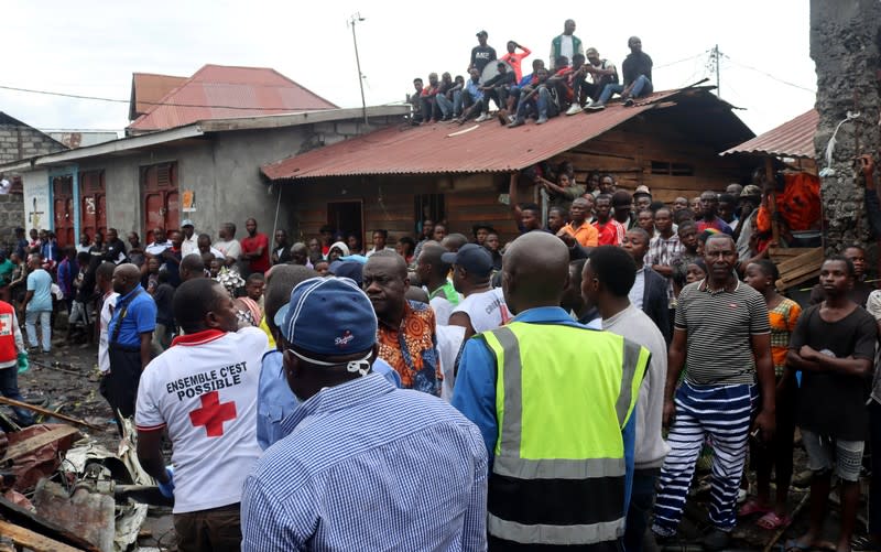 Rescuers and civilians gather at the site where a Dornier 228-200 plane operated by local company Busy Bee crashed into a densely populated neighborhood in Goma