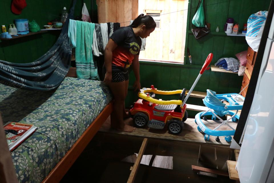 Valeria Ribeiro de Souza walks on a wooden plank that keeps furniture above floodwater inside her home in Anama, Amazonas state, Brazil