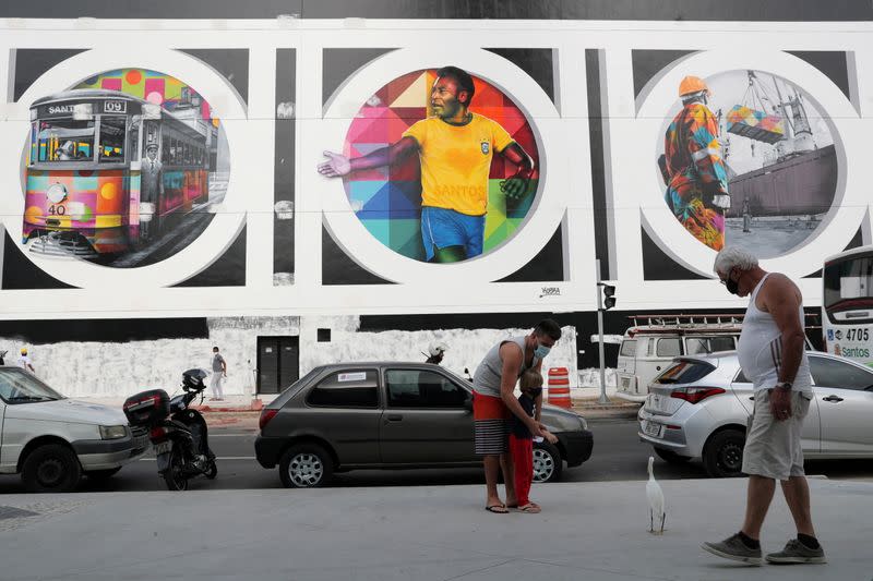 People walk in front of a mural depicting Brazilian soccer legend Pele in Santos