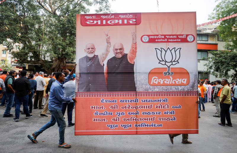 FILE PHOTO: FILE PHOTO: Supporters of India's ruling Bharatiya Janata Party (BJP) carry a hoarding of Indian Prime Minister Narendra Modi and Union Minister of Home Affairs Amit Shah for celebrations in Ahmedabad