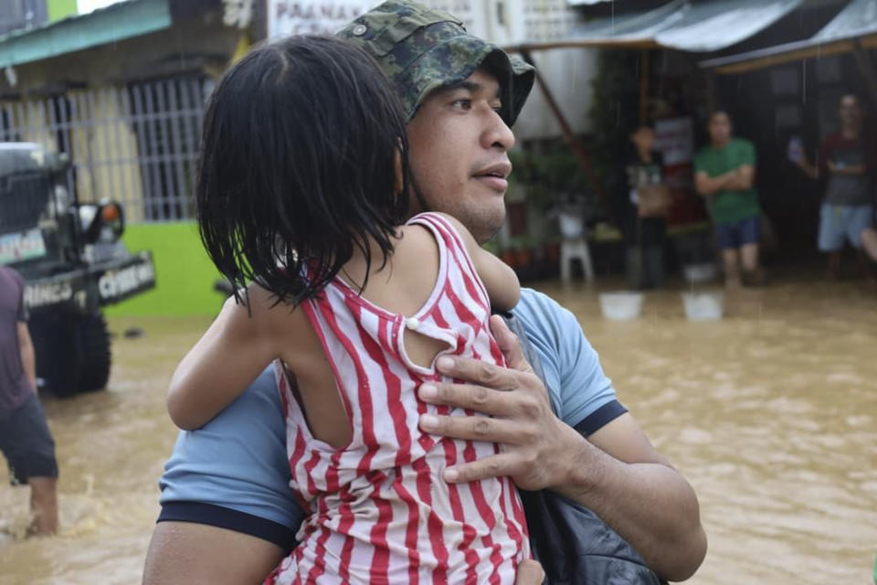 In this photo provided by the Philippine Coast Guard, a rescuer carries a child to safer grounds as floods rose due to Tropical Storm Nalgae at Parang, Maguindanao province, southern Philippines on Friday Oct. 28, 2022. (Philippine Coast Guard via AP)
