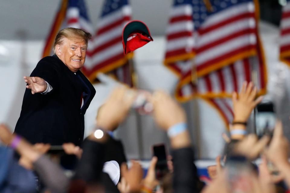 Former President Donald Trump throws a "Make America Great Again" hat into the crowd before speaking at a "Save America Rally" in Commerce, Ga., on Saturday, March 26, 2022.