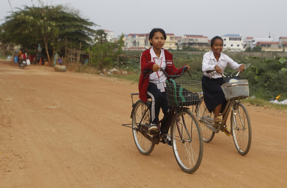 Schoolgirls cycle home after class of Phnom Penh, Cambodia, Friday, April 26, 2019. Phnom Penh, Cambodia. Cambodian authorities have ordered a one-hour reduction in the length of school days because of concerns that students and teachers may fall ill from a prolonged heat wave. (AP Photo/Heng Sinith)