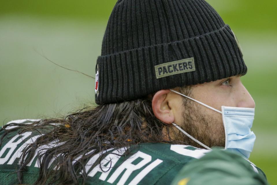 Green Bay Packers' David Bakhtiari wears a facemask on the bench during the first half of an NFL football game against the Jacksonville Jaguars Sunday, Nov. 15, 2020, in Green Bay, Wis. (AP Photo/Mike Roemer)