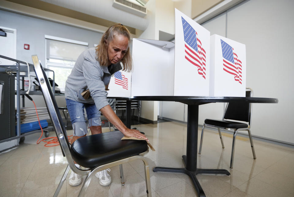 A precinct volunteer sanitizes a chair to prepare for the next voter in Iowa's Primary Election at the Polk County Central Senior Center, Tuesday, June 2, 2020, in Des Moines, Iowa. (AP Photo/Charlie Neibergall)