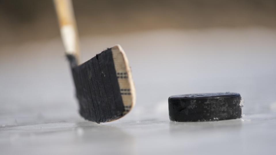 A hockey stick and puck on an ice rink