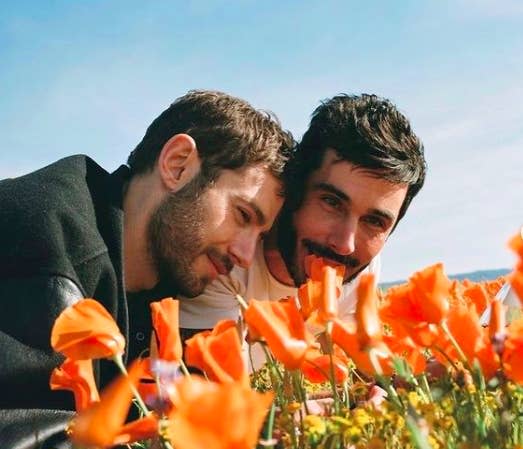 The couple laying next to a bed of flowers