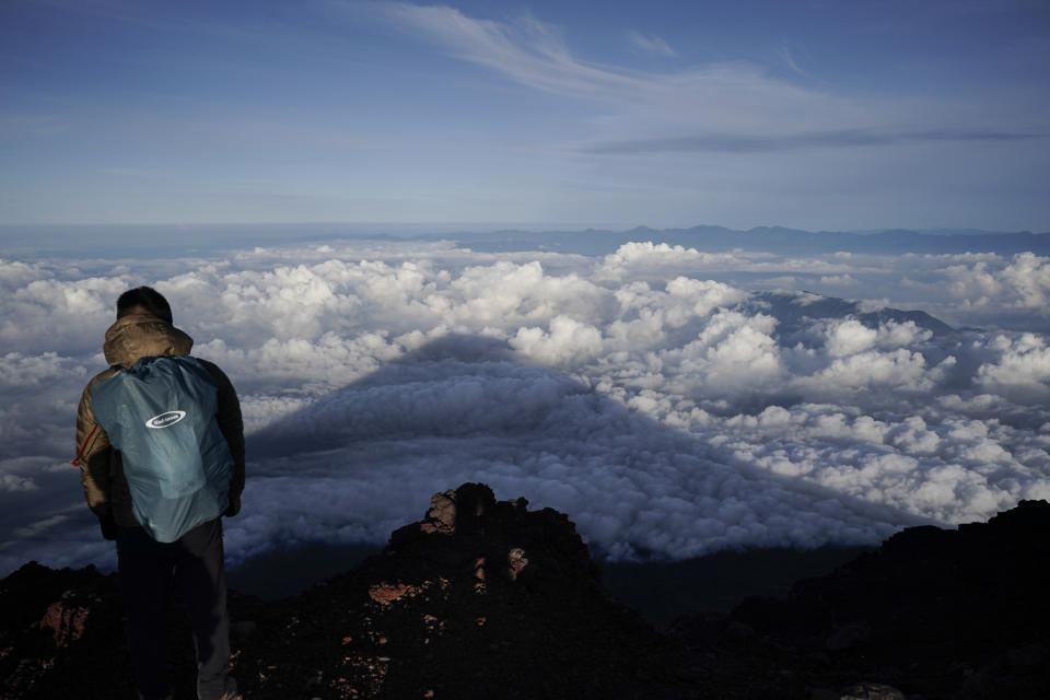 FILE - The shadow of Mount Fuji is casted on clouds hanging below the summit, Tuesday, Aug. 27, 2019, in Japan. Those who want to climb one of the most popular trails of the iconic Japanese Mount Fuji will now have to reserve ahead and pay a fee as the picturesque stratovolcano struggles with overtourism, littering and those who attempt rushed “bullet climbing,” putting lives at risk. (AP Photo/Jae C. Hong, File)