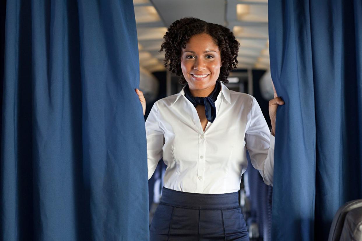 Flight attendant holding curtains on plane