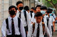 Some students from La Salle College wear masks, which have been banned at protests under emergency powers, as they walk to school in Hong Kong