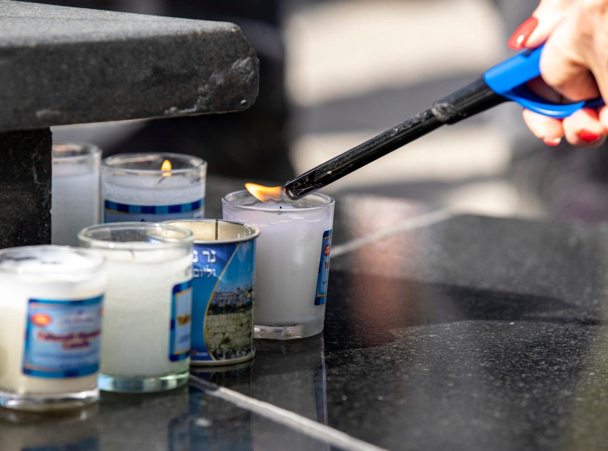 Family members of Holocaust survivors light candles, one for every million Jews killed in the Holocaust at the foot of the memorial at Civic Park in Palm Desert, Calif., Friday, Jan. 26, 2024.