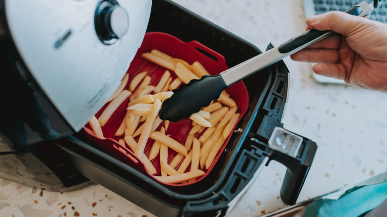 Person arranging french fries in air fryer
