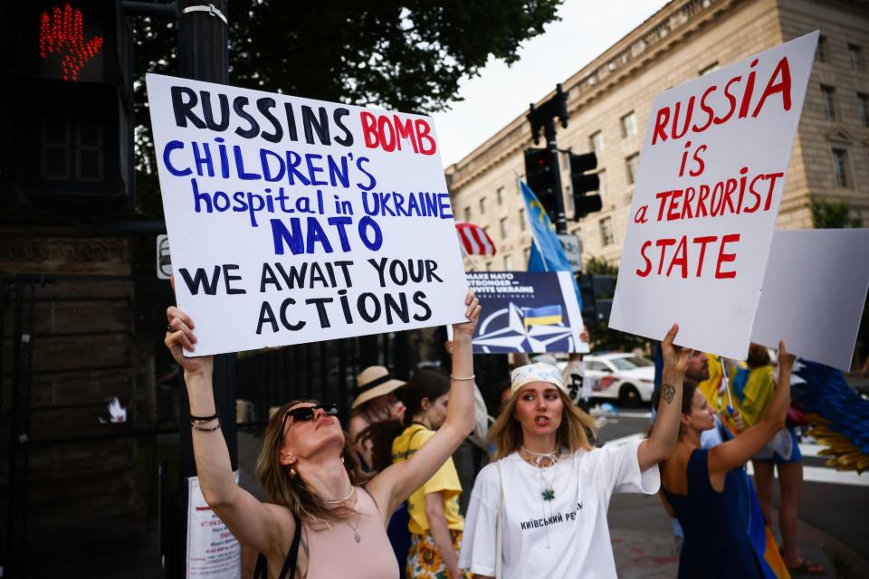 Ukraine supports hold up hand-painted signs demanding NATO take action after Russia's strike