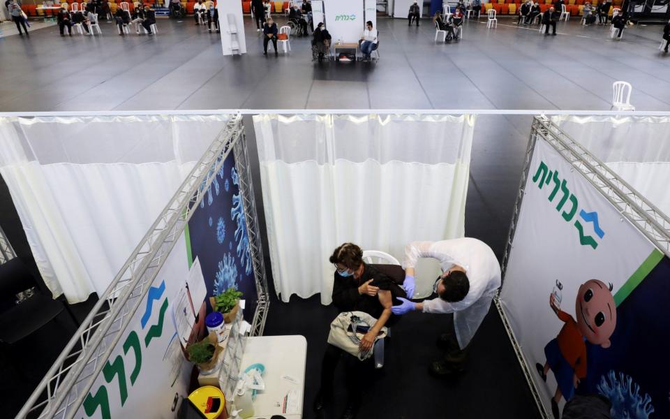 A woman receives her Covid-19 vaccine at a temporary healthcare centre, at a basketball court in Petah Tikva - Ammar Awad/Reuters