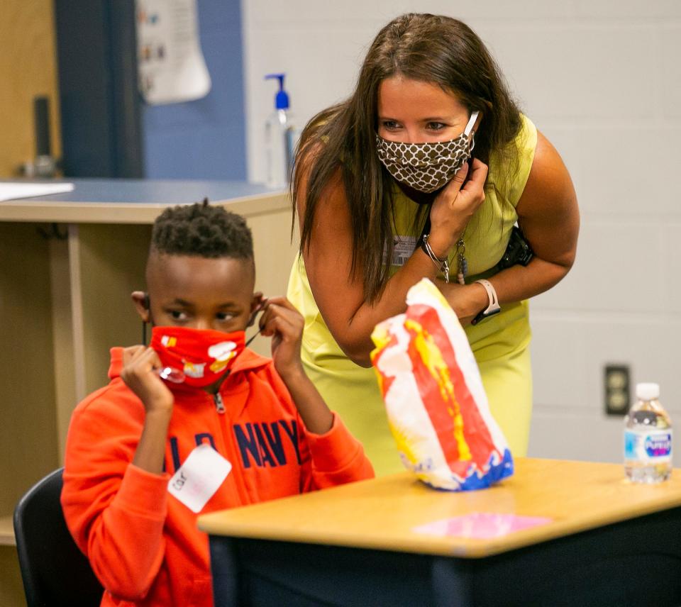 Former Evergreen Elementary School Principal Ashley Kemp talks with a fourth-grade student while he fixes his mask in July 2020 at Evergreen.