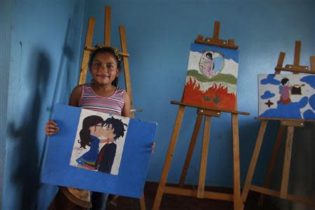 A girl poses with a drawing in a Centro Alcance at the Nueva Capital impoverished neighbourhood in Tegucigalpa November 28, 2013. REUTERS/Tomas Bravo