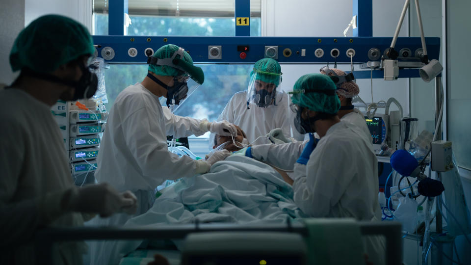 Health workers wearing masks, face shields and gloves attend to a man with COVID-19 as he lies on a hospital bed in Huesca, Spain.