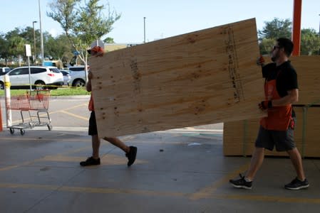 Men lift a sheet of plywood at a Home Depot store ahead of the arrival of Hurricane Dorian in Titusville