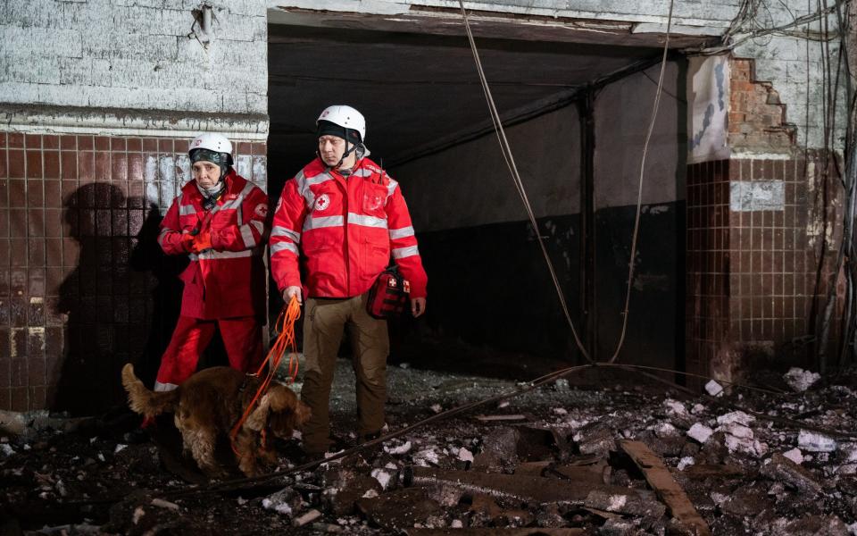 Two search and rescue workers stand with their dog at a badly-damaged apartment block in Kharkiv, north-eastern Ukraine