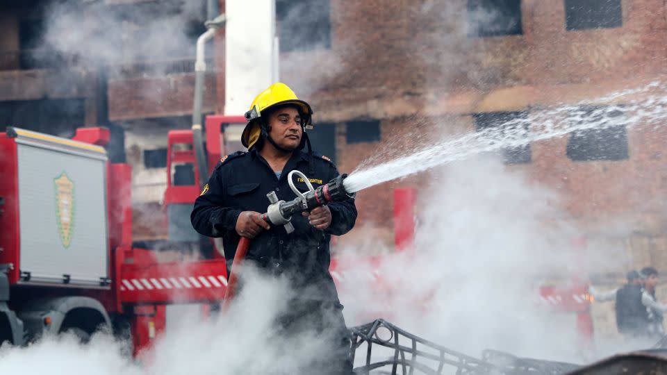 A firefighter cools the area as it continues to smoulder. - Momen Samir/AFP/Getty Images
