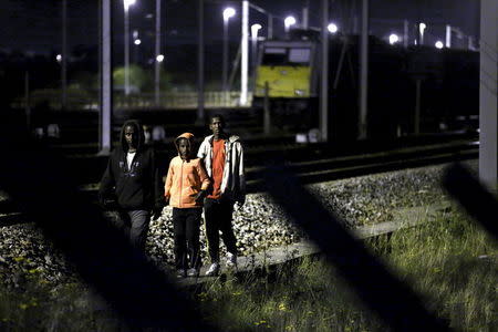 Migrants make their way along train tracks as they attempt to access the Channel Tunnel in Frethun, near Calais, France, August 2, 2015. REUTERS/Pascal Rossignol