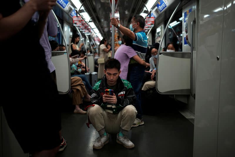 VJ Kawakubo, de 30 años, programador informático, consulta su teléfono en un tren subterráneo de Shanghái, China