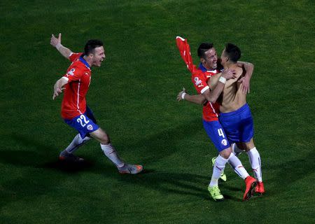 Alexis Sanchez (R) celebrates with teammates Mauricio Islas (C) and Angelo Henriquez after scoring his penalty kick during a shootout against Argentina in the Copa America 2015 final soccer match at the National Stadium in Santiago, Chile, July 4, 2015. REUTERS/Ricardo Moraes