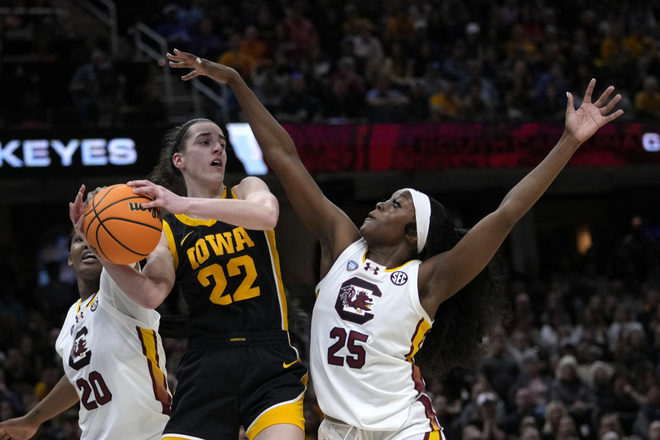 Iowa guard Caitlin Clark (22) passes over South Carolina guard Raven Johnson (25) during the first half of the Final Four college basketball championship game in the women's NCAA Tournament, Sunday, April 7, 2024, in Cleveland. (AP Photo/Carolyn Kaster)