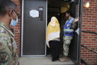 Service members look on as an Afghan refugee walks inside a temporary housing facility in Liberty Village on Joint Base McGuire-Dix- Lakehurst in Trenton, N.J., Thursday, Dec. 2, 2021. (Barbara Davidson/Pool via AP)