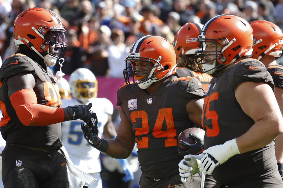 Cleveland Browns running back Nick Chubb (24) celebrates with tight end David Njoku (85) and guard Joel Bitonio (75) after scoring a touchdown against the Los Angeles Chargers during the first half of an NFL football game, Sunday, Oct. 9, 2022, in Cleveland. (AP Photo/Ron Schwane)
