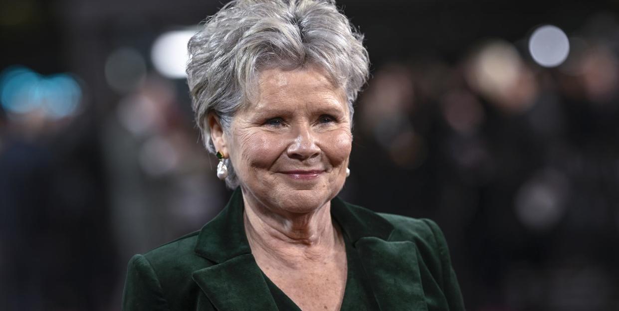 imelda staunton, wearing a green suit, smiles as she attends a red carpet event