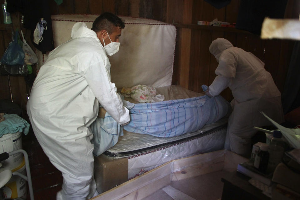 Public funeral service workers remove the body of Amelia Dias Nascimento, 94, who died from complications related to COVID-19 in her home, in Manaus, Amazonas state, Friday, Jan. 22, 2021. The number of people who die in their homes amid the new coronavirus pandemic is growing due to the lack of availability in hospitals and the shortage of oxygen. (AP Photo/Edmar Barros)