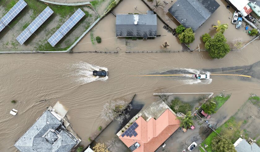 This aerial view shows cars through a flooded roadway in Planada, California, as an "atmospheric river" continues on January 10, 2023. - Relentless storms were ravaging California again Tuesday, the latest bout of extreme weather that has left 14 people dead. Fierce storms caused flash flooding, closed key highways, toppled trees and swept away drivers and passengers -- reportedly including a five-year-old-boy who remains missing in central California. (Photo by JOSH EDELSON / AFP) (Photo by JOSH EDELSON/AFP via Getty Images)