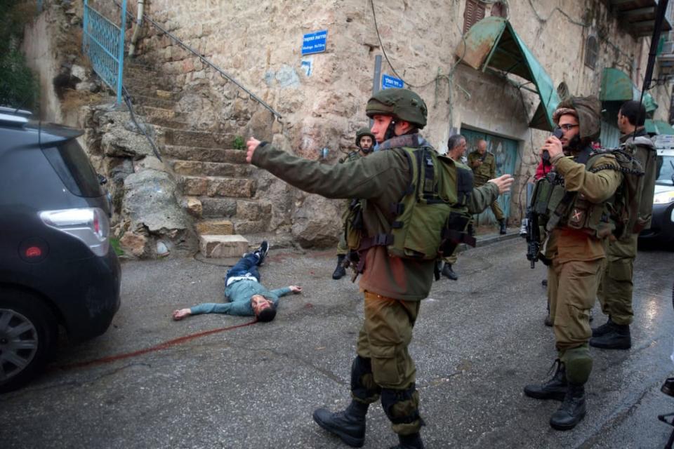 A photograph of Israeli soldiers around the body of a Palestinian man who tried to stab a soldier at the Jewish settlement of Beit Hadassah during the “Knife Infitada” on October 29, 2015.