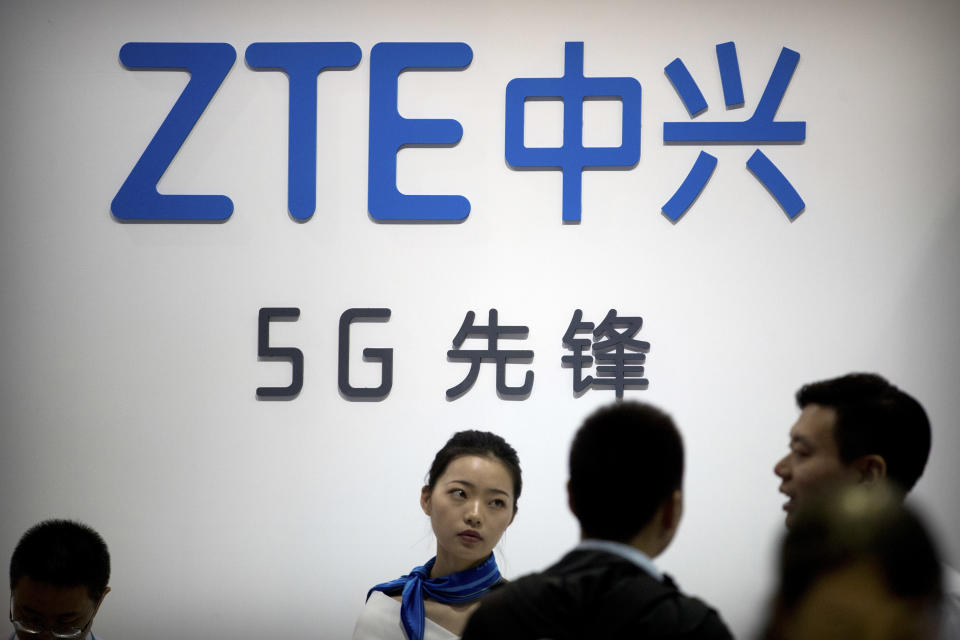 FILE - In this Sept. 26, 2018, file photo, staff members stand at a display for Chinese technology firm ZTE at the PT Expo in Beijing. Chinese tech stocks Lenovo Group and ZTE Corp. have tumbled in Hong Kong following a news report Chinese spies might have used chips supplied by another company to hack into U.S. computer systems. (AP Photo/Mark Schiefelbein, File)