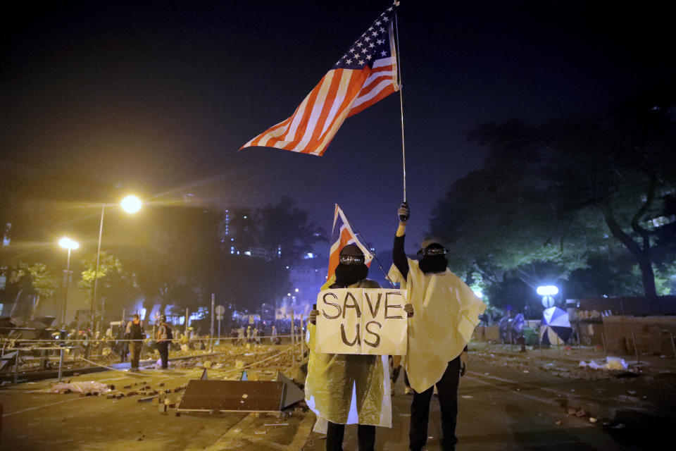 FILE - In this Nov. 18, 2019, file photo, protesters hold British and American flags and a sign reading "Save us" as they stand near Hong Kong Polytechnic University after police gave protesters an ultimatum to leave the campus in Hong Kong. From Tokyo to Brussels, political leaders have swiftly decried Beijing's move to impose a tough national security law on Hong Kong that cracks down on subversive activity and protest in the semi-autonomous territory. But the rhetoric from democratic nations has more bark than bite. (AP Photo/Kin Cheung, File)